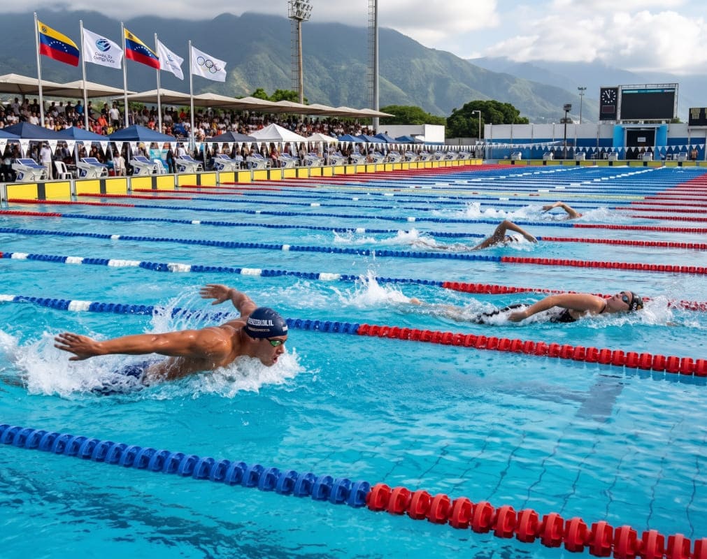 Nadador de élite compitiendo en estilo mariposa en una piscina olímpica, ilustrando las características principales de la natación.