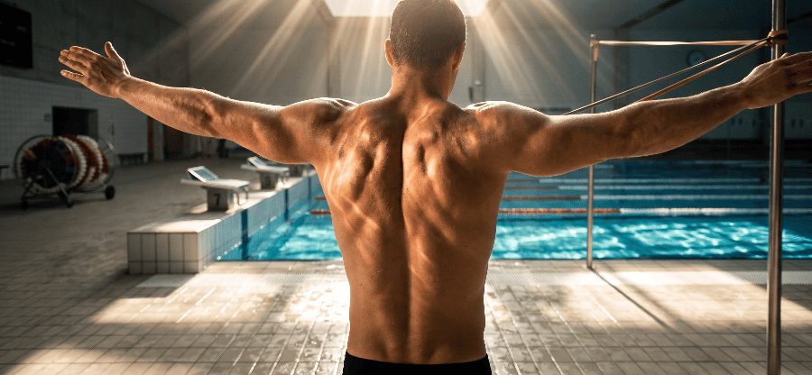 nadador al borde de la alberca realizando estiramientos de apertura pectoral y movilidad de hombros con bandas elásticas para prevenir el hombro de nadador y mejorar la postura fuera del agua, optimizando la alineación corporal en natación.